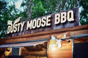 A close-up of the illuminated sign on the Dusty Moose food trailer.